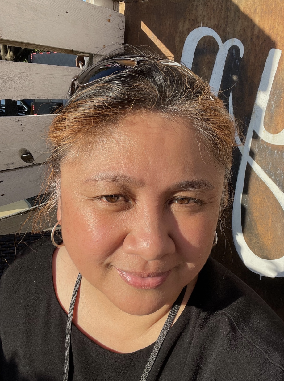 a selfie of a woman looking slightly upward. She has brown and black hair and is wearing a black shirt.